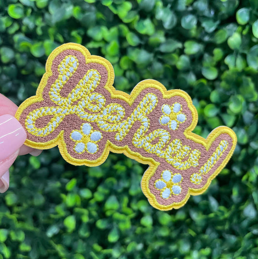 Decorative patch with 'Yeehaw!' text held against a green leafy background