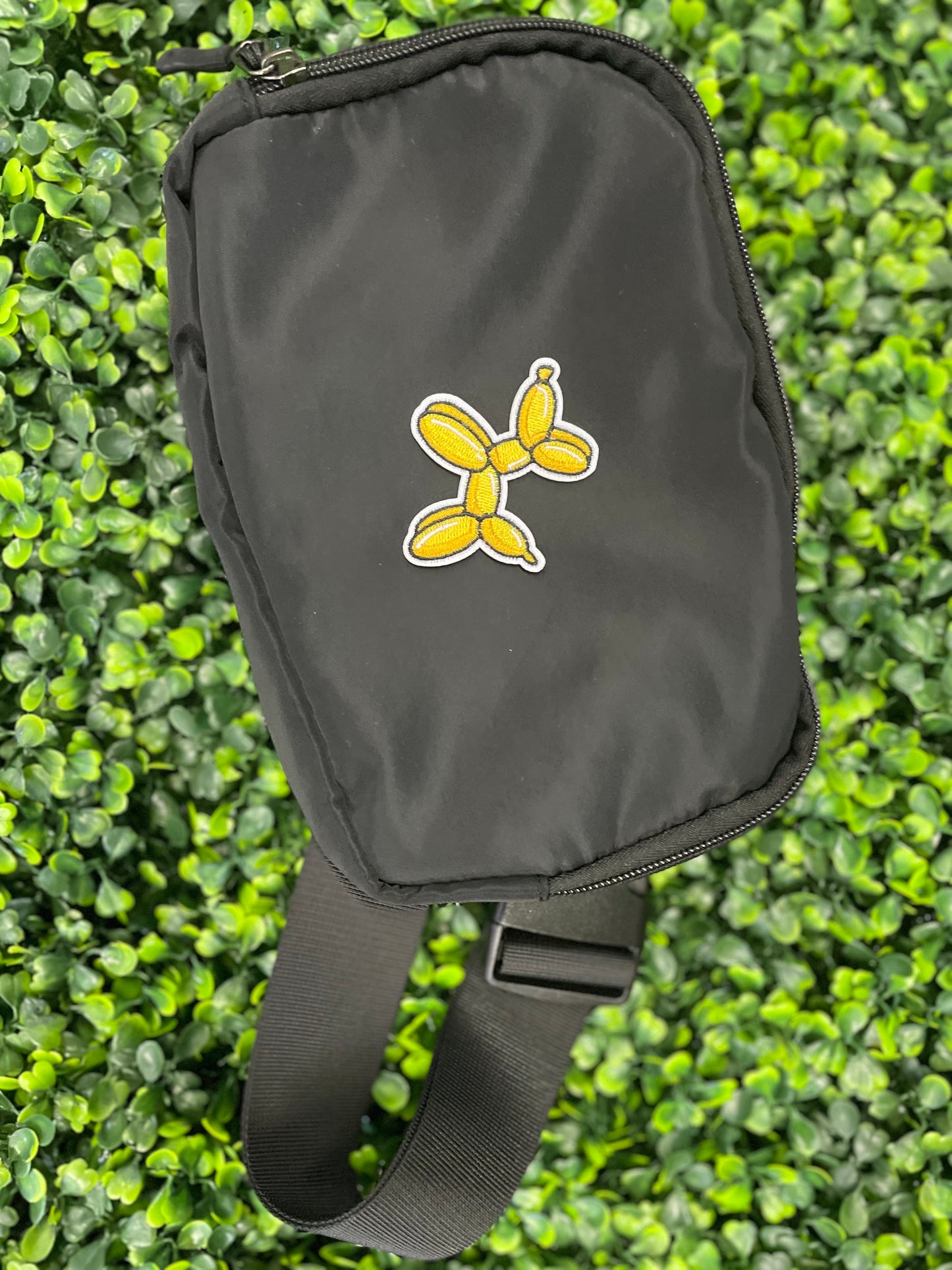 Yellow balloon dog-shaped patch placed on a black shoulder bag