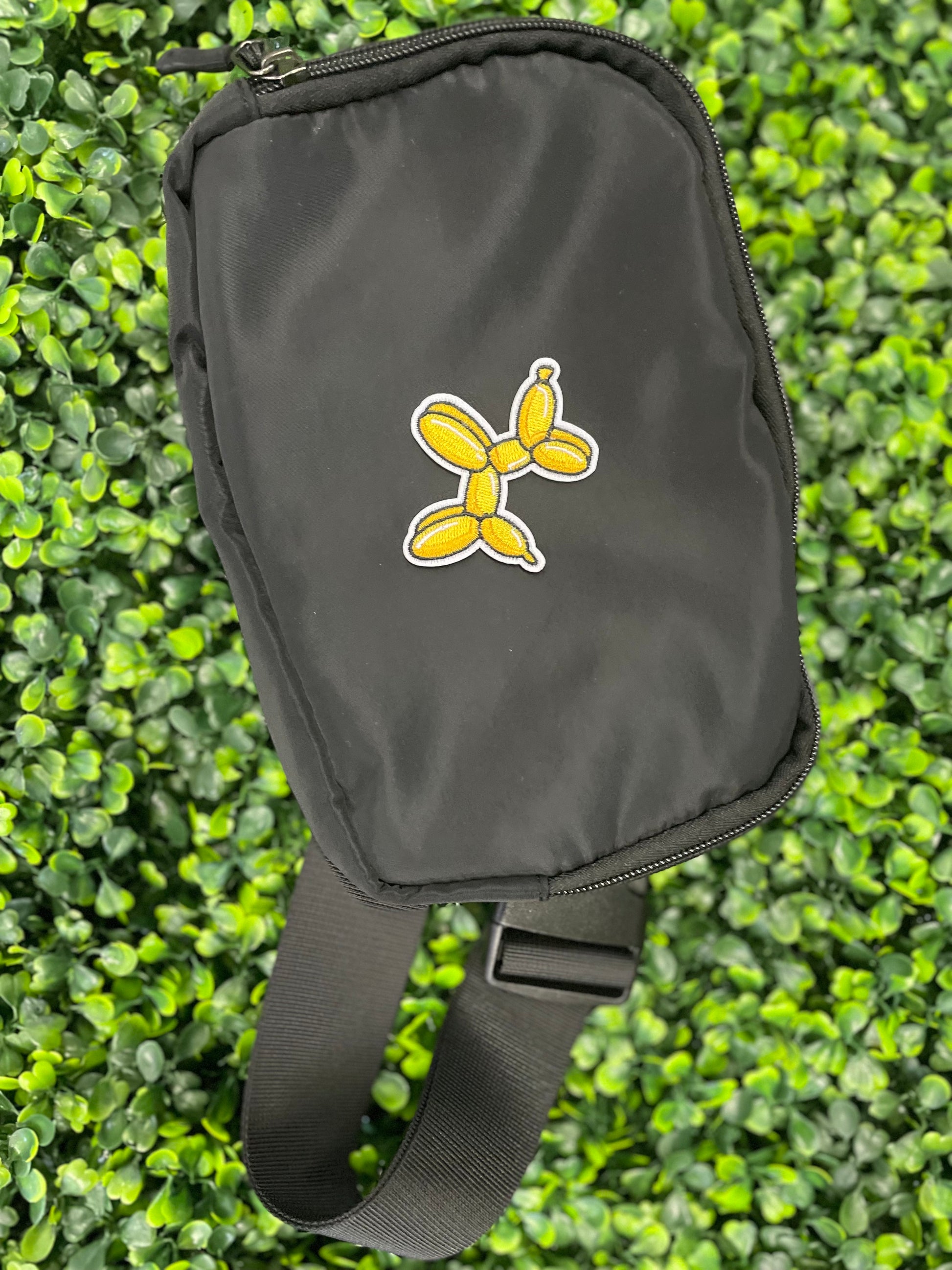 Yellow balloon dog-shaped patch placed on a black shoulder bag
